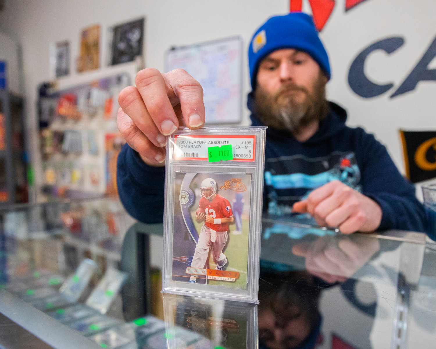 Dan Keiper holds up a Tom Brady rookie card valued at $1,100 inside Keiper’s Cards in downtown Centralia on Thursday.