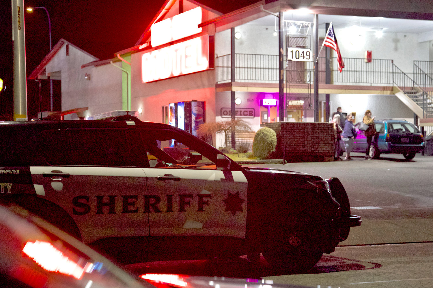 Bystanders outside the King Oscar Motel in the 1100 block of Eckerson Road watch a standoff between law enforcement and an armed individual occurring on private property across the street Sunday night. 