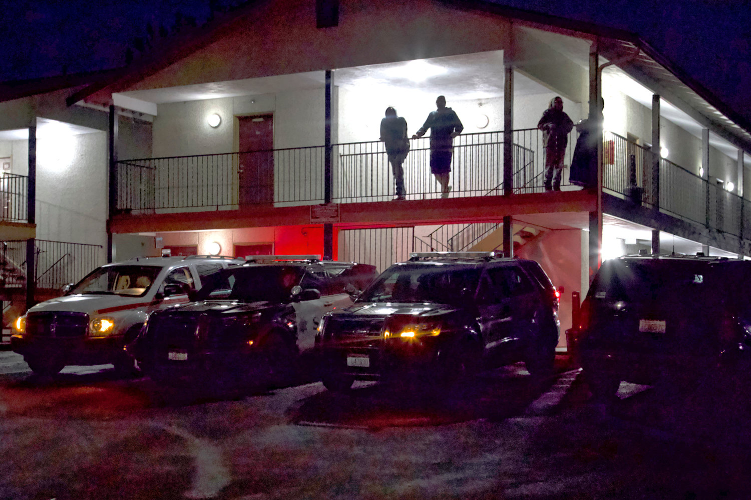 Bystanders at the King Oscar Motel in the 1100 block of Eckerson Road watch a standoff between law enforcement and an armed individual occurring on private property across the street Sunday night. 