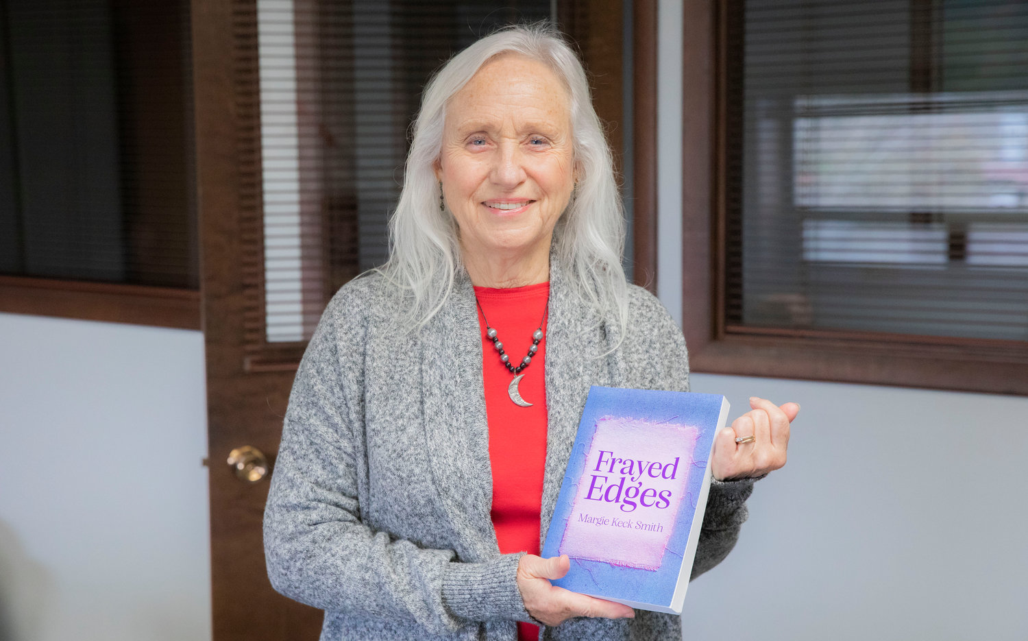 Margie Keck Smith smiles for a photo with her new book titled ”Frayed Edges” in Centralia on Tuesday, Jan. 17.