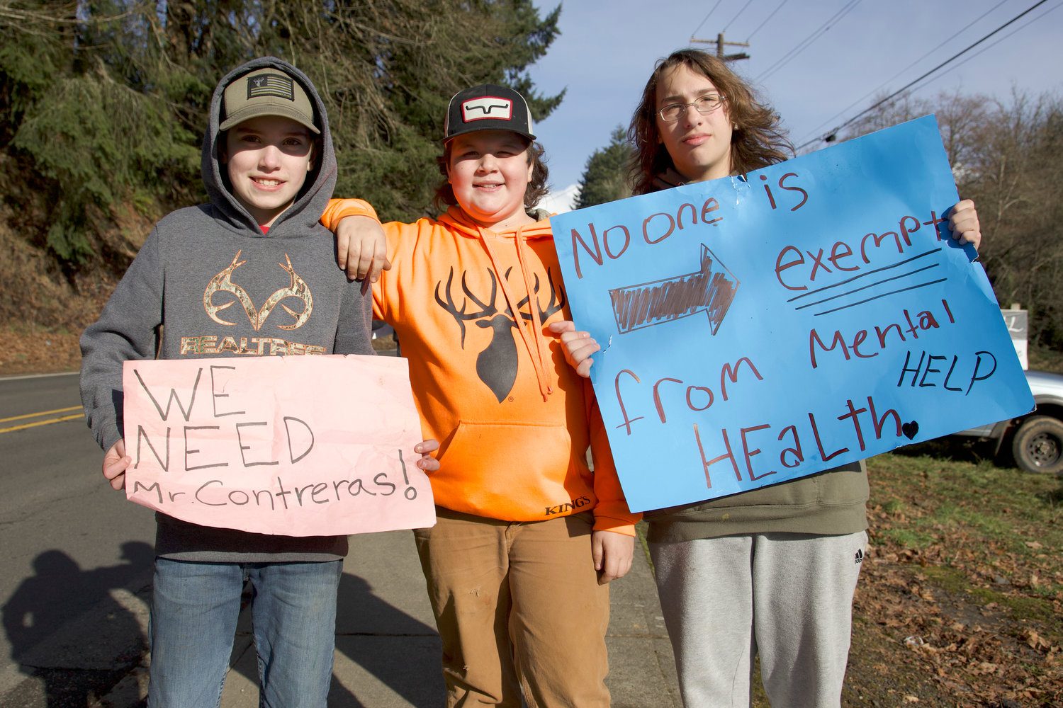Winlock 6th-grader, Dylin, center, and 8th-graders Tucker and Xavier stand with their signs protesting Winlock School District counselor layoffs Wednesday afternoon in Winlock.