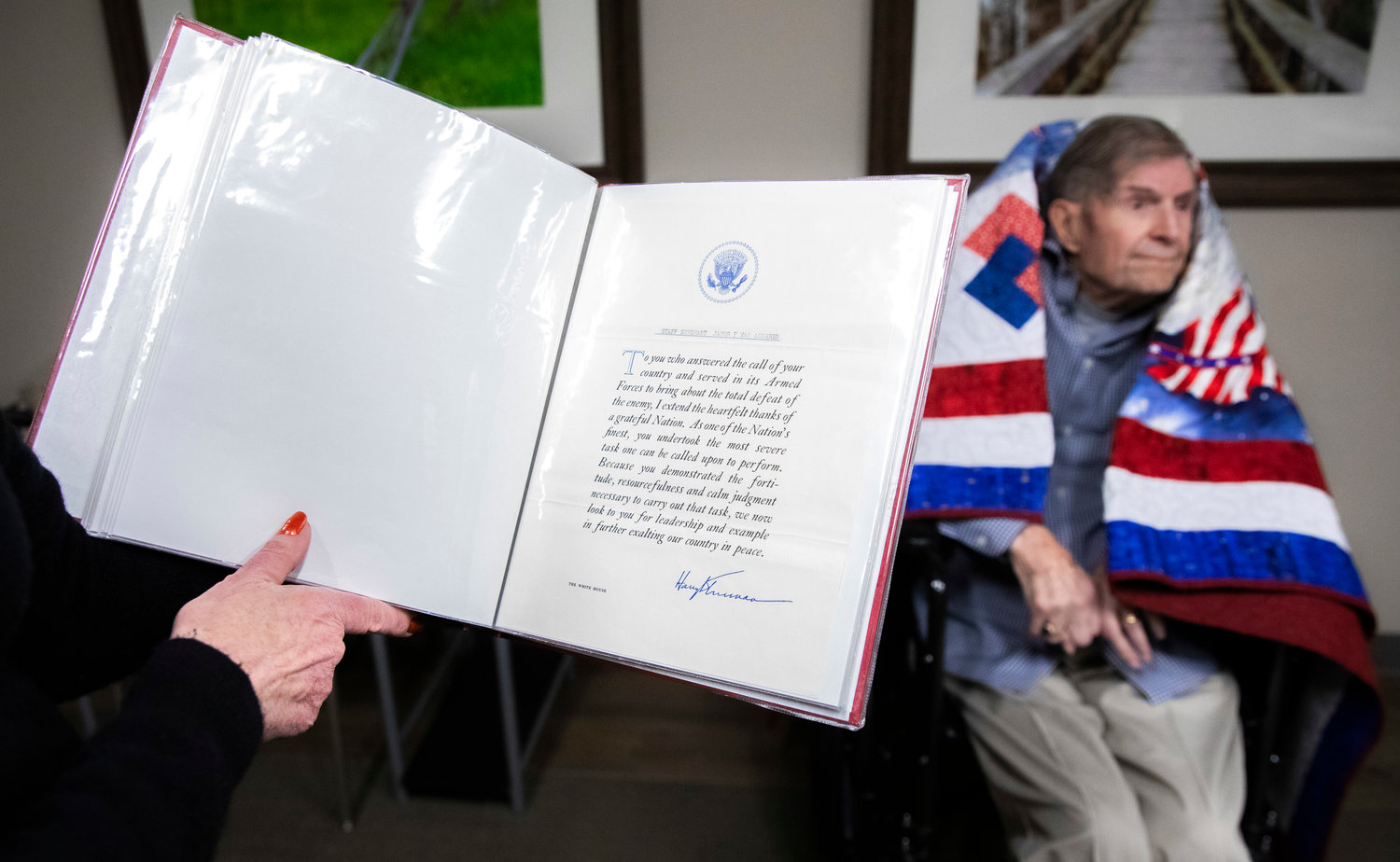 James F. Van Ackeren, a WWII veteran who served as a staff sergeant in the U.S. Army, sits while wrapped in a blanket from Quilts of Valor at Woodland Estates in Chehalis on Thursday in front of a letter he received from President Harry S. Truman.
