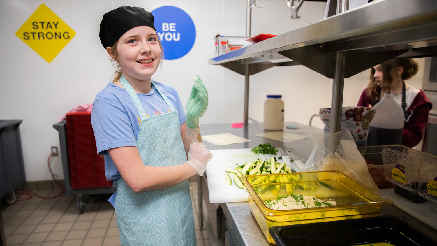 Tru Hamrick, 11, smiles while putting on gloves in preparation to make zucchini fries which would earn her the top spot in the Future Chefs National Challenge at Orin Smith Elementary in Chehalis on Thursday.