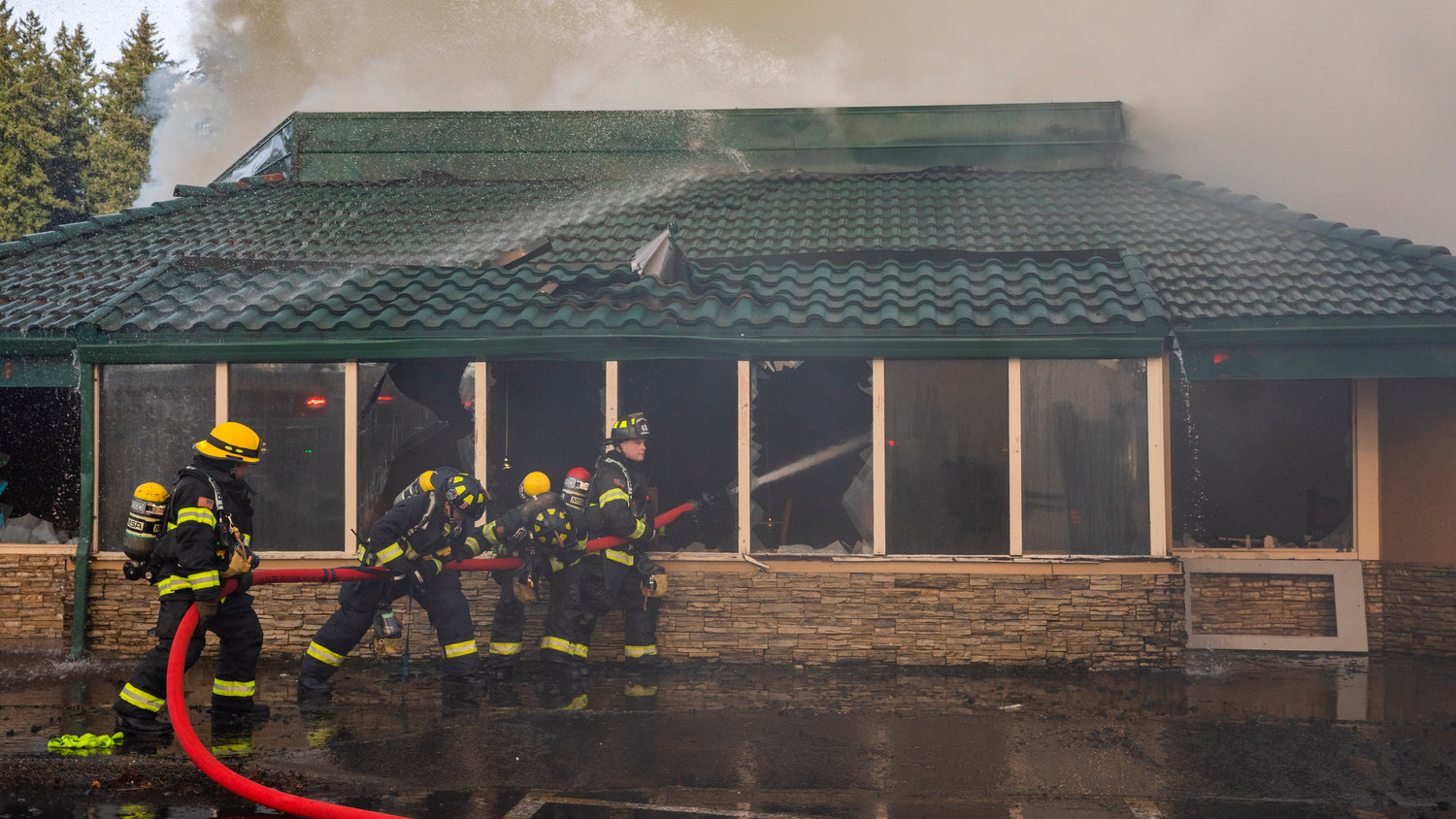 A Riverside firefighter works with Chehalis Fire crews to put out flames inside the former location of Papa Pete’s and Shari’s Cafe in Centralia on Sunday.