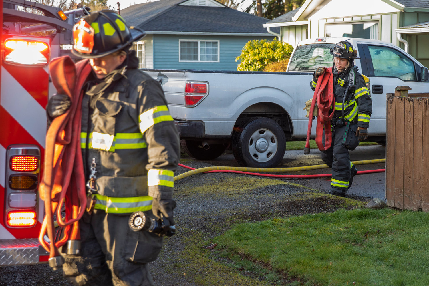 Crews from Riverside Fire Authority carry hoses along View Avenue in Centralia where a detached garage and items inside were damaged by flames Wednesday morning.