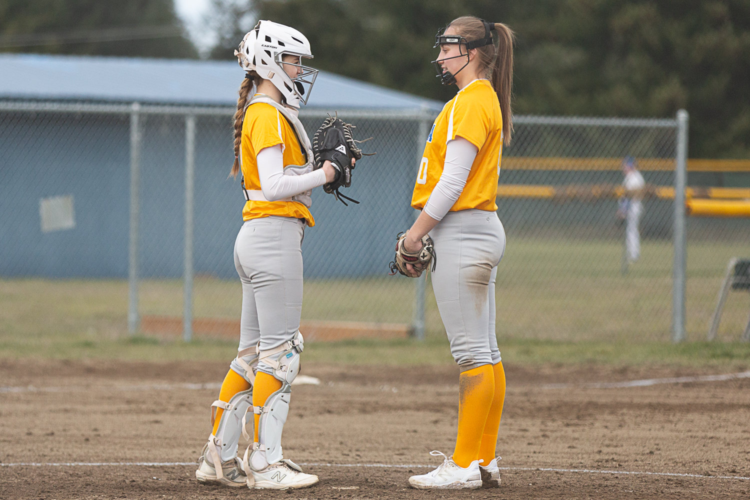 Adna's Brooklyn Loose (left) and Karlee VonMoos (right) chat between pitches against Rochester March 15.