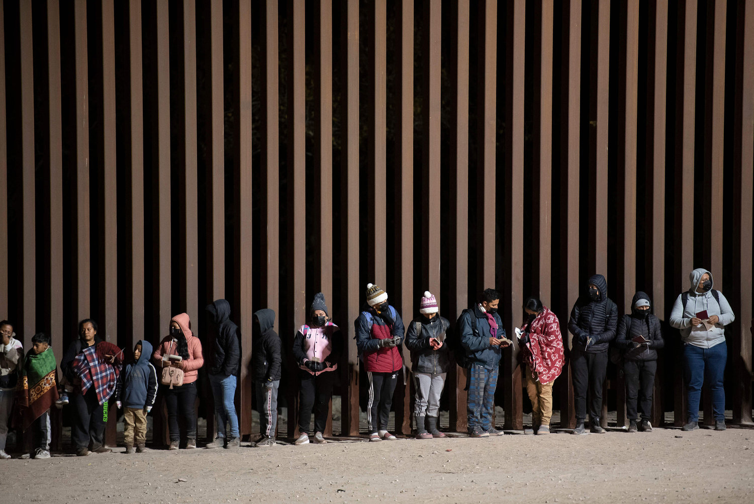 Asylum-seekers line up to be processed by U.S. Customs and Border Patrol agents at a gap in the US-Mexico border fence near Somerton, Arizona, on Dec. 26, 2022. (Rebecca Noble/AFP/Getty Images/TNS)