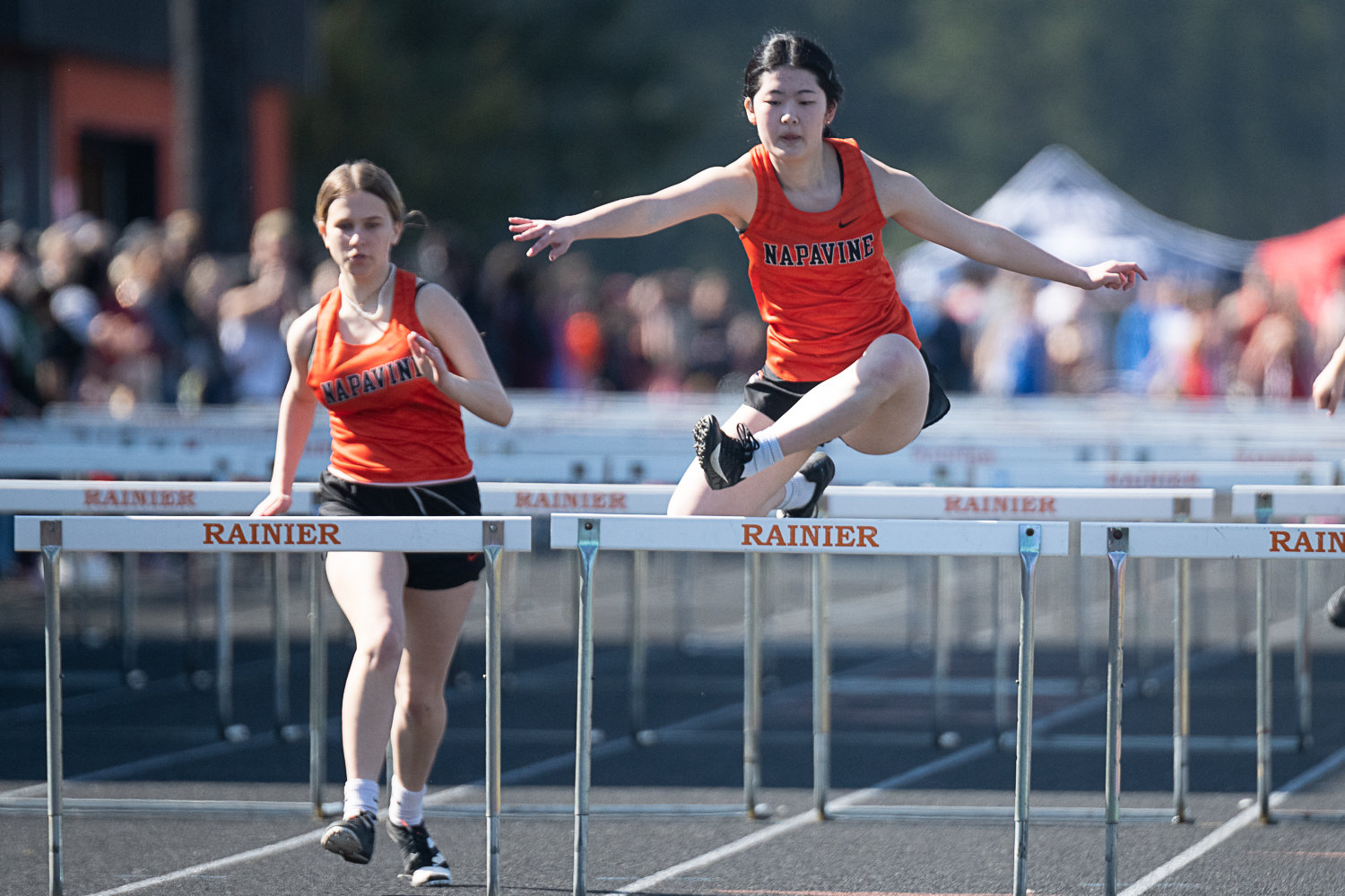 Napavine's Emily Kang clears the final hurdle, with Jaynalee Anders right on her heels, in the girls 100-meter hurdles at the Rainier Icebreaker on March 18.