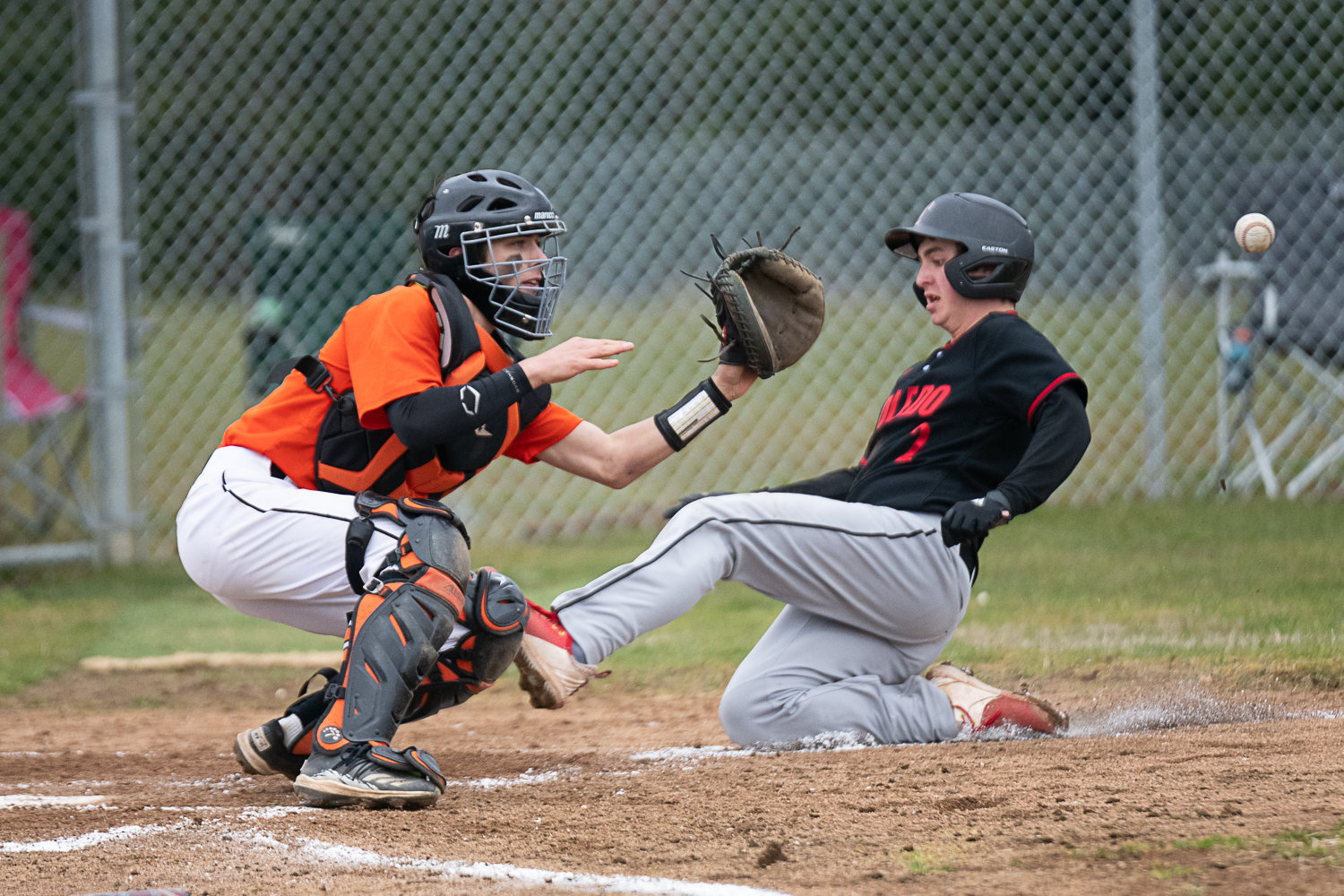 Napavine catcher sees the ball come home for a plate at the plate as Toledo's Ryker Sorenson slides home, during the first of two games between the Tigers and the Riverhawks on March 20.