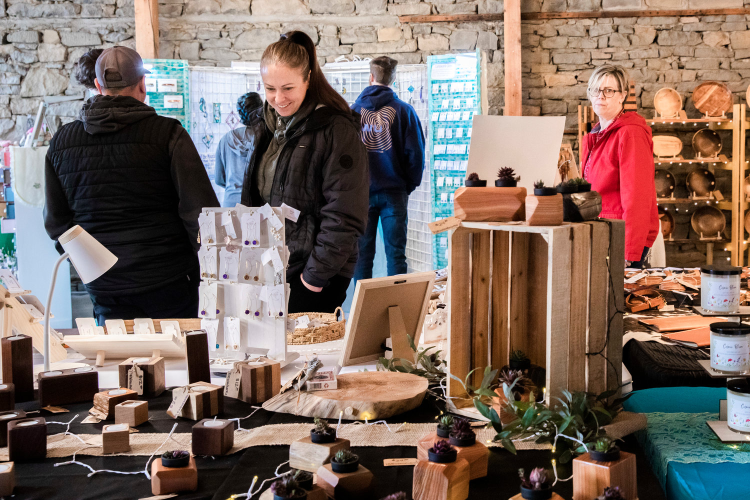 Vistors smile and look on at items on display during the Tenino Arts Spring Market featuring 32 regional artisans inside the Kodiak Room on Sunday.