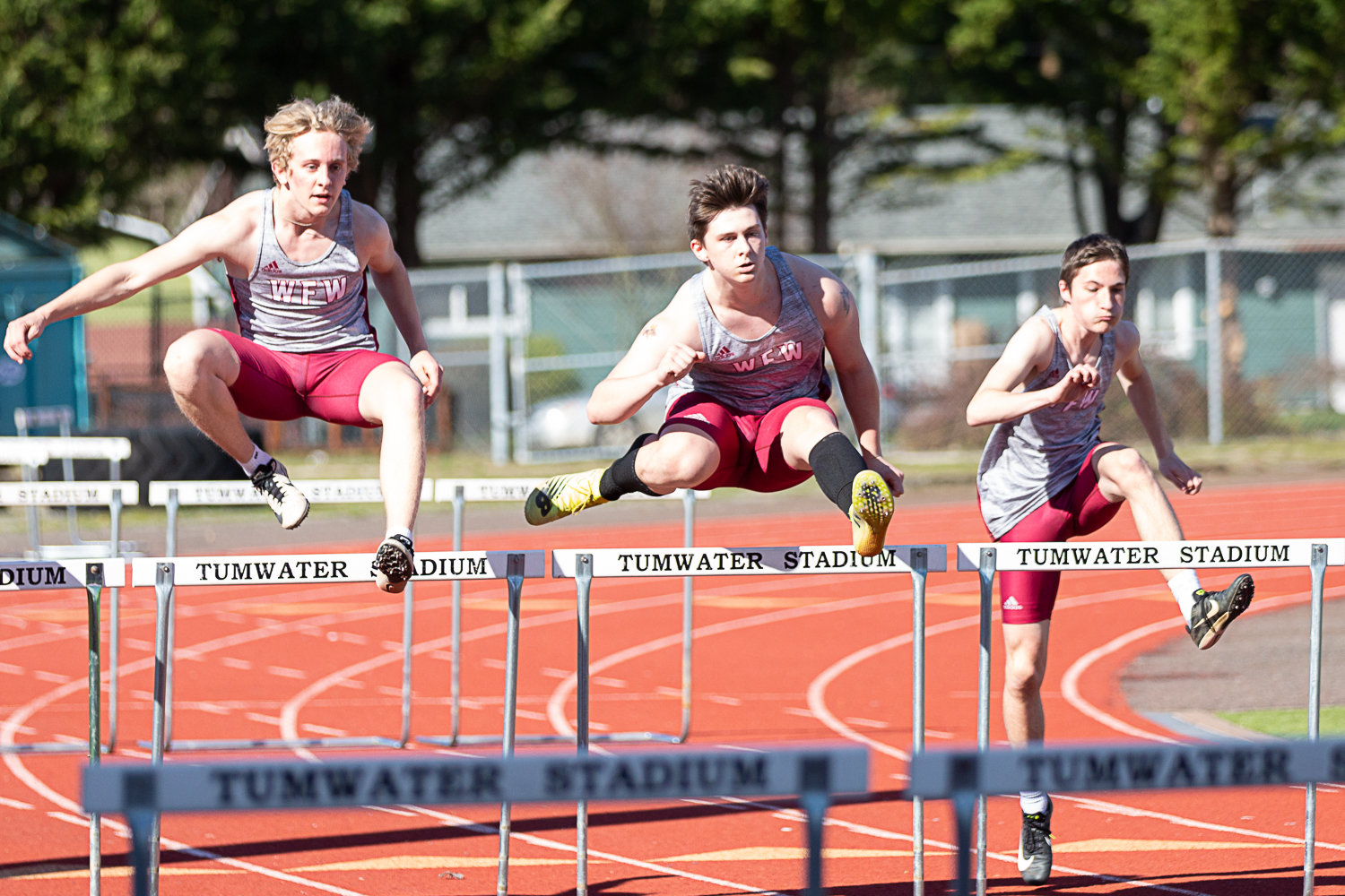A trio of W.F. West hurdlers leap over an obstacle at Tumwater District Stadium March 29.
