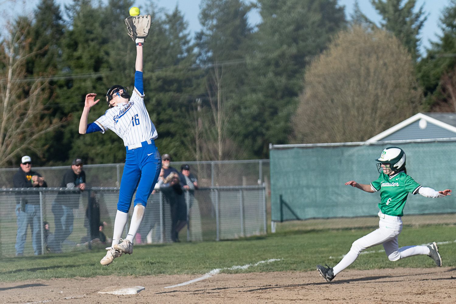 Rochester third baseman Kassidy Byrd goes up to corral a wild throw as Chloe Foos slides safely into third, during Tumwater's 5-3 win over the Warriors on March 29,