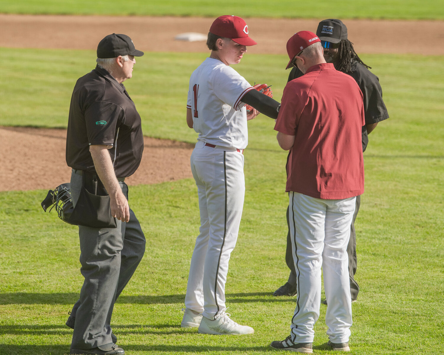 W.F. West coaching staff makes an adjustment to Riggs Westlund’s sleeve before he was able to pitch, as requested by the opposing team, during a game against Mark Morris at Bearcat Stadium in Chehalis on Tuesday, May 9.