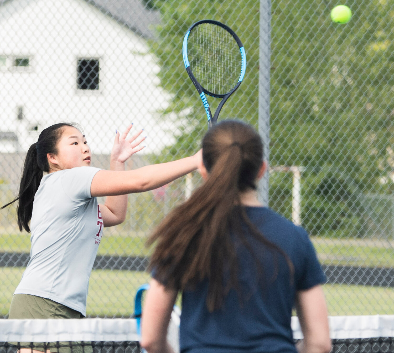 W.F. West first doubles player Laura Yip hits a high backhand volley against Black Hills player Stella Moore in the Evergeen Conference league championship match against on Tuesday.