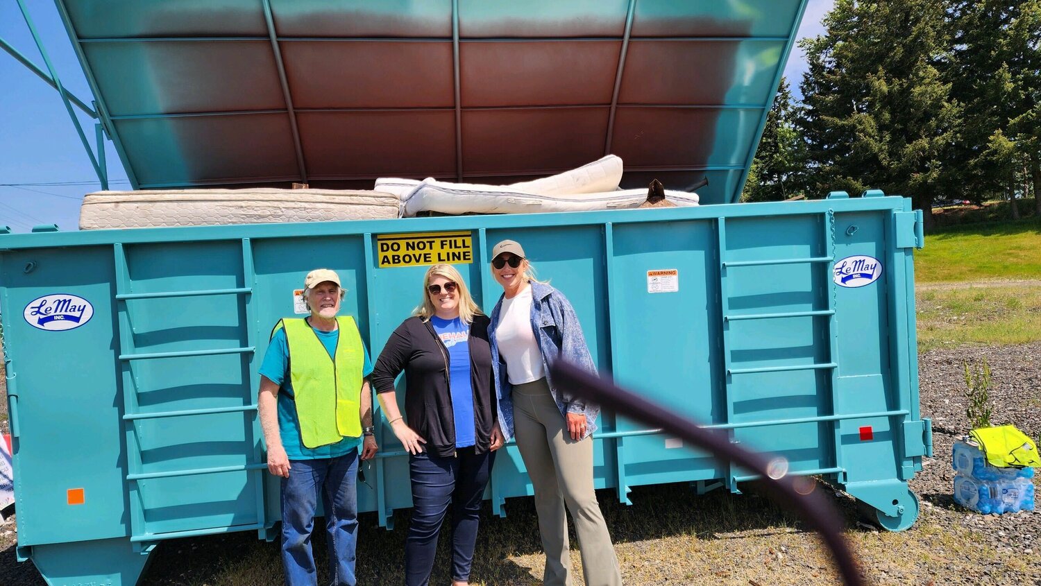 Chehalis Mayor Tony Ketchum, Experience Chehalis Executive Director Annalee Tobey and Visiting Nurses Foundation Executive Director Jacki Jewell are pictured in front of a full LeMay Inc. dumpster at the Chehalis Fire Station. Photo courtesy City of Chehalis. 