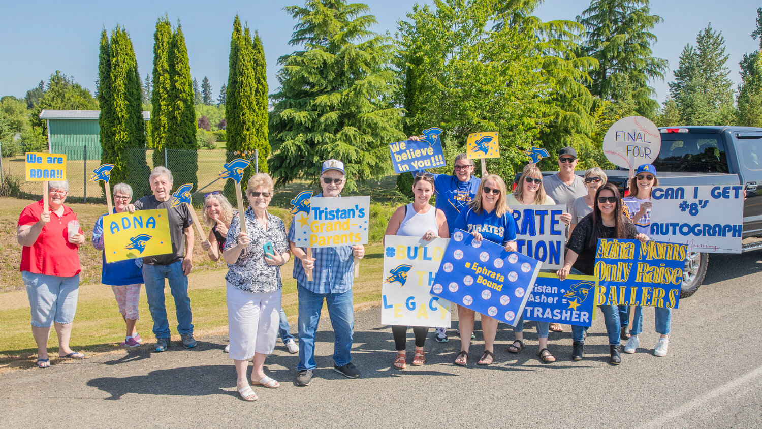Pirate fans and family pose for a photo while holding signs for the Adna High School baseball team as they leave for state appearances on Thursday, May 25.