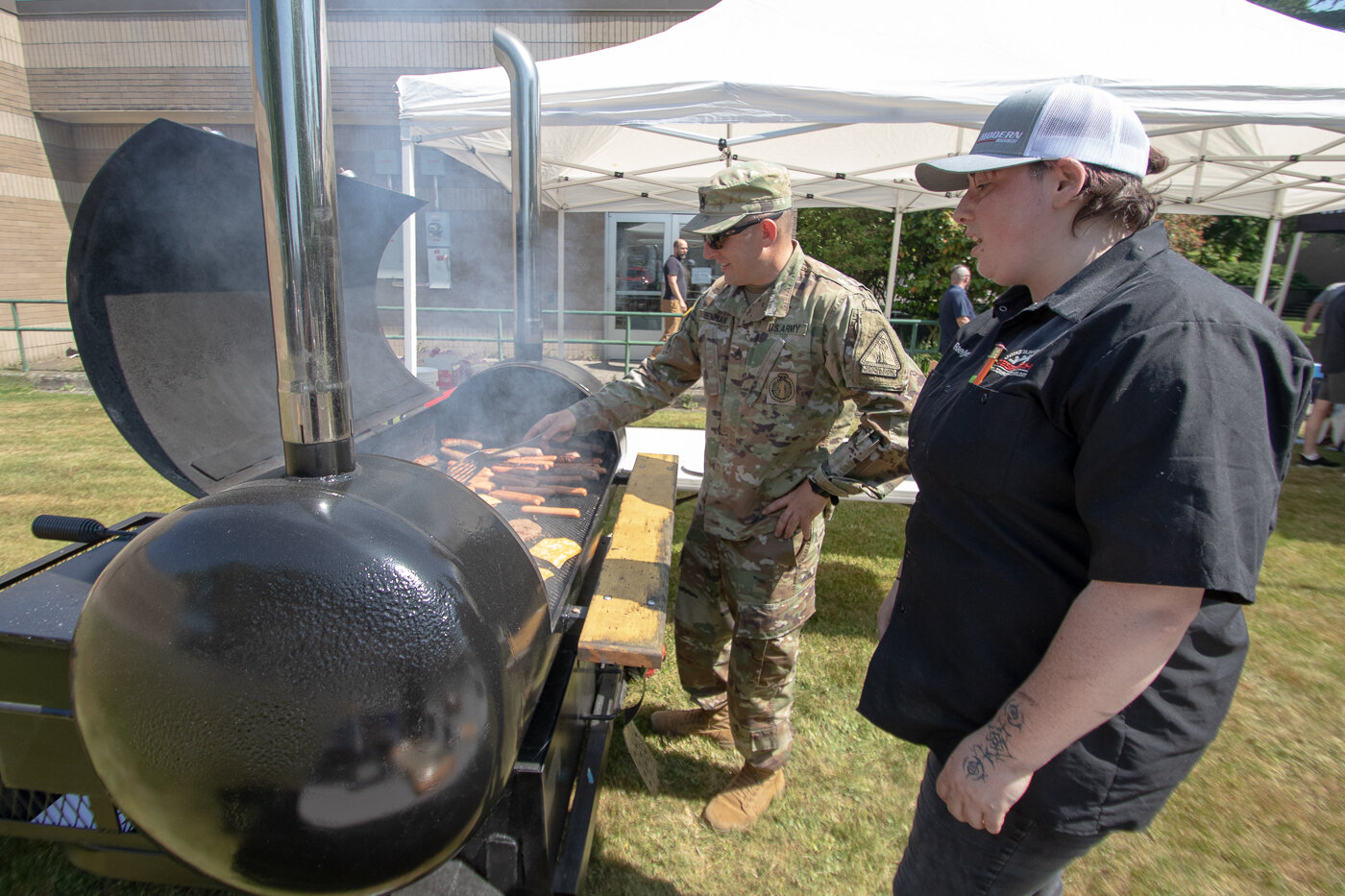 Washington Army National Guard Staff Sergeant James Benham works the grill alongside Raelynn Kuljis, Centralia College diesel tech program member and U.S. Air Force veteran, at a BBQ following the college's Memorial Day ceremony on Thursday.