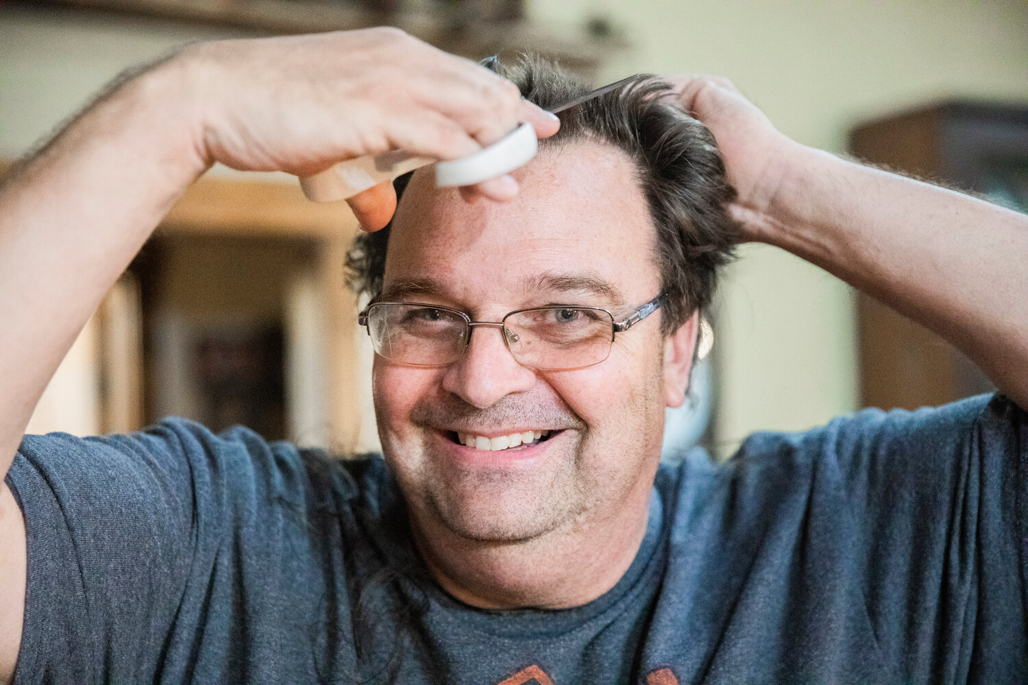 Ken Wiseman smiles while holding a pair of scissors to his hair making cuts to raise awareness for Tonja Vlach, a receptionist at I-5 Toyota, who is undergoing chemotherapy for breast cancer and an auction the family is holding online to raise funds this weekend.