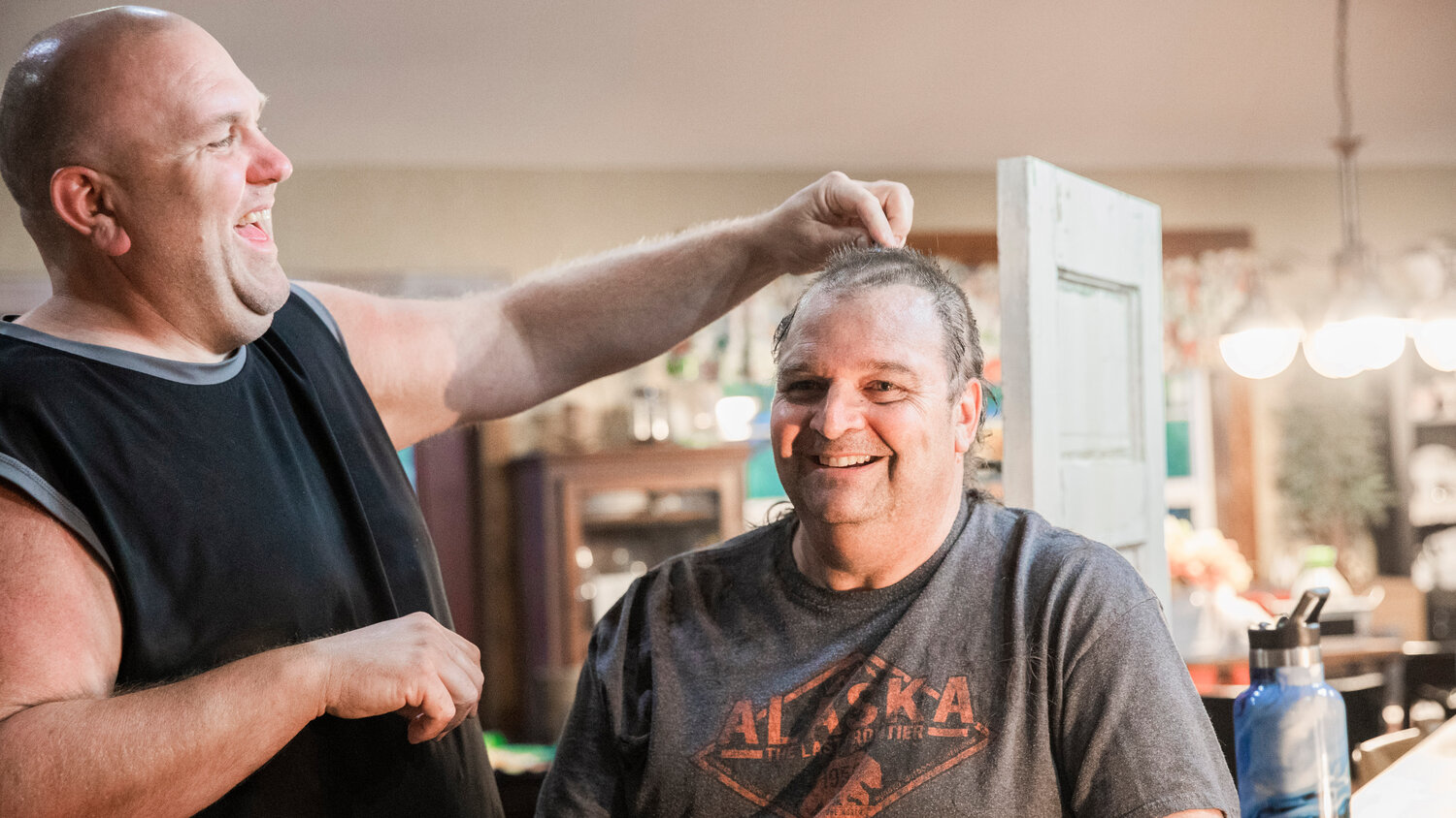 Ty Vlach smiles as he cuts Ken Wiseman’s hair to raise awareness for his sister Tonja Vlach, a receptionist at I-5 Toyota, who is undergoing chemotherapy for breast cancer and an auction the family is holding online to raise funds this weekend.