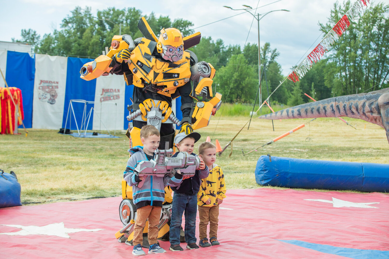 From left, Centralia kids Colton, 5, Kohen, 5, and Emerson, 3, pose for a photo with Bumblebee, the Transformer, at the Southwest Washington Fairgrounds during the Jordan World Circus show on Wednesday, May 31.