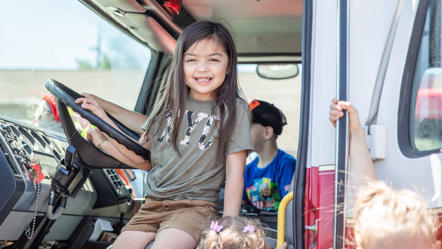 Kindergarten students smile while sitting behind the wheel of a fire engine during a visit to Lewis County Fire District 5 in Napavine on Tuesday, June 7.