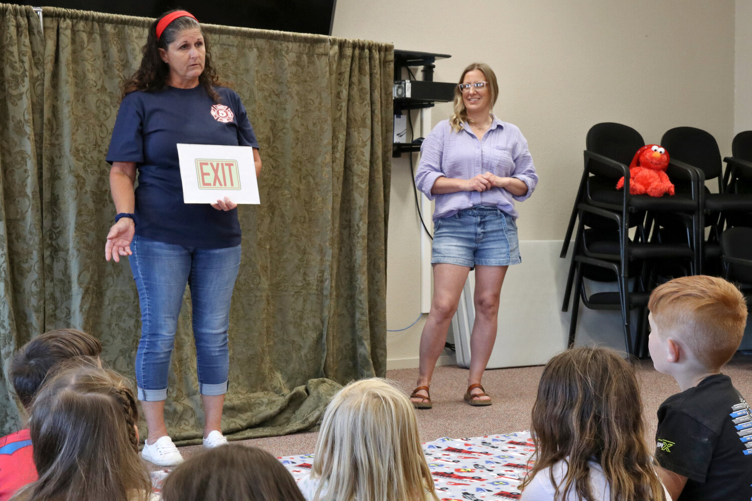 Lewis County District 5 employees Carmen Sundin Jessica Blair explain the importance of exit signs to visiting Napavine Elementary School kindergarteners in Napavine on Tuesday, June 6.