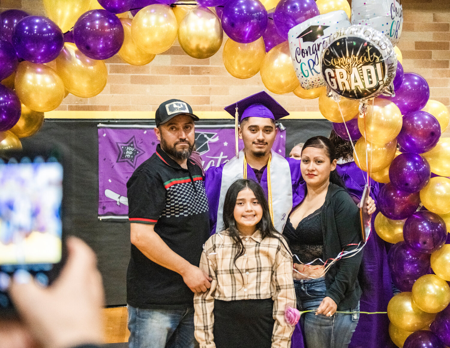 Juan Carlos Cerseda smiles for a photo in the Onalaska High School gym on Friday with his family after graduating with high honors, meaning he had a cumulative GPA between 3.5 and 3.99 for his time at Onalaska High School.