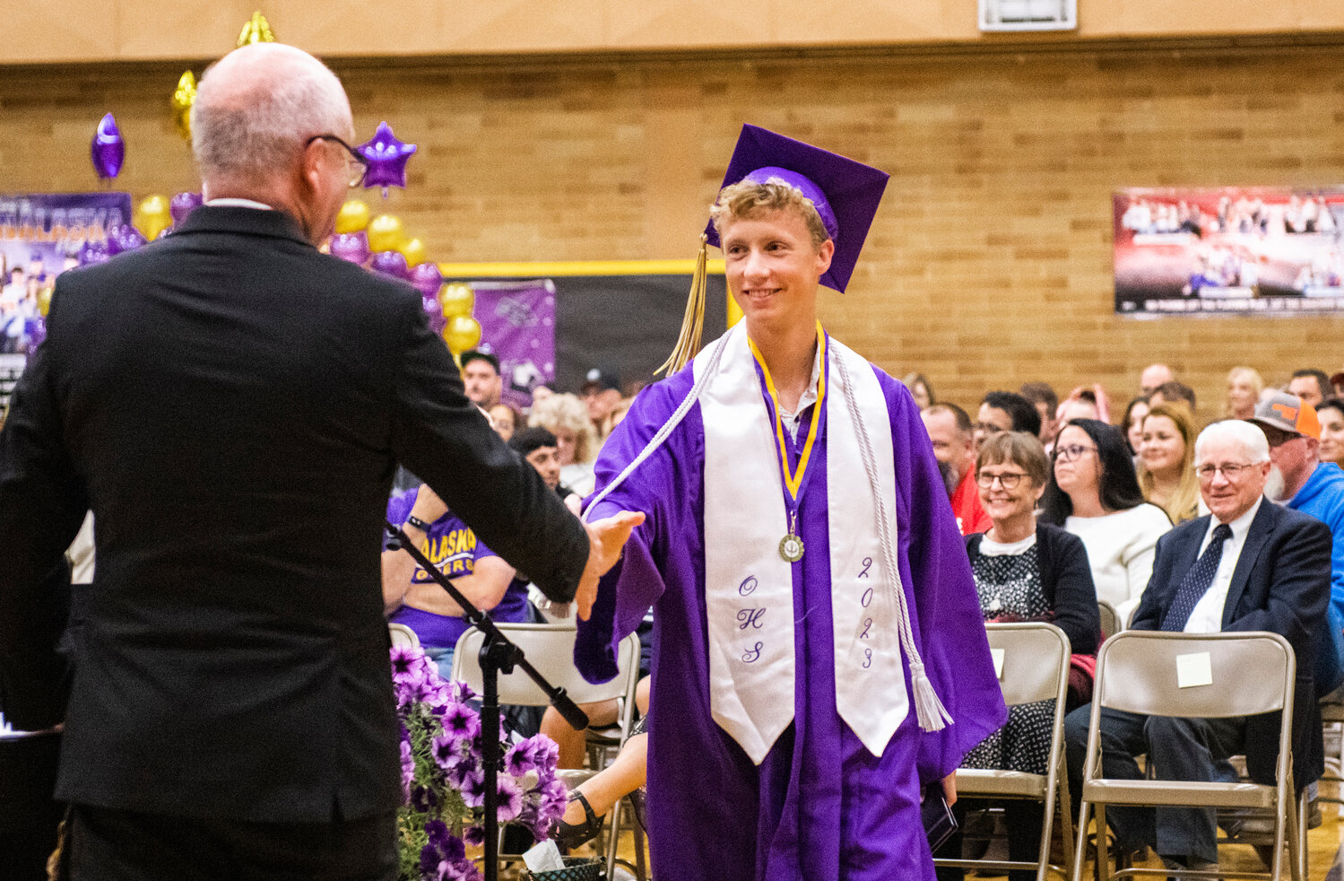 Onalaska High School graduating senior Benjamin Russon shakes hands with the principal after being awarded his diploma, honors for his GPA and a staff award noting him as the class’ most athletic boy on Friday.