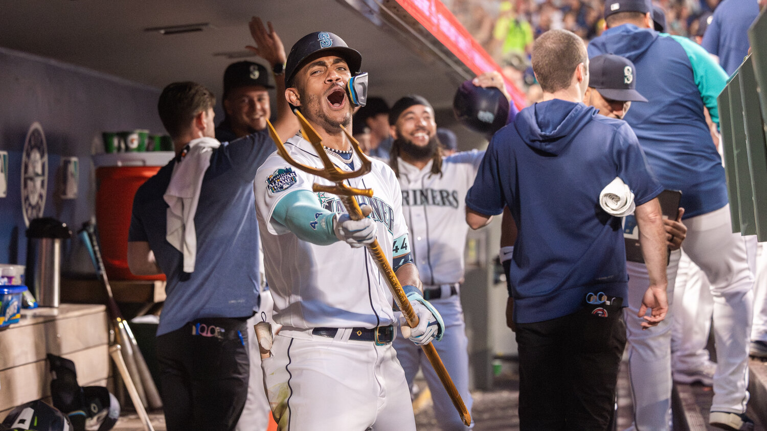 Julio Rodríguez celebrates a home run as J. P. Crawford smiles and receives high-fives behind him inside the Mariners dugout at T-Mobile Park in Seattle on Monday, Aug. 28.