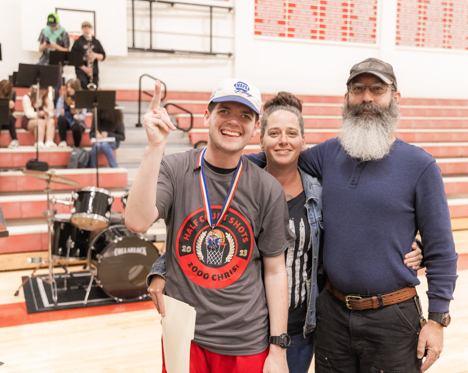 Chris Harvey smiles for a photo with his parents Brian and Terry after sinking a shot to mark 2,000 made half-court buckets at Toledo High School on Thursday, Sept. 21.