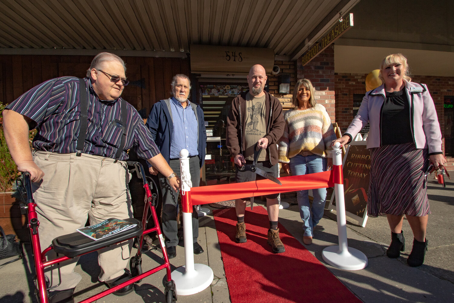 Mitch Moberg, owner of Bigfoot Treasure, prepares to cut the ribbon at his business in downtown Chehalis as Chehalis City Councilor Daryl Lund, left, mayor Tony Ketchum, second from left, and Lindy Waring and Christine Brower look on.