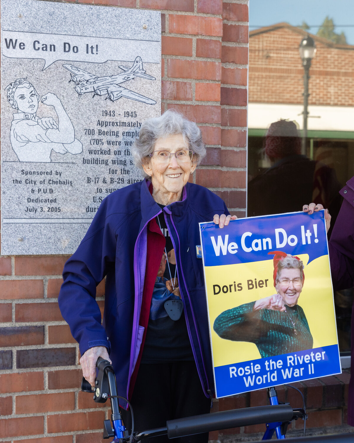 Doris Bier smiles for a photo alongside a “Rosie The Riveter,” plaque, honoring Boeing employees who crafted wing sections for the B-17 and B-29 aircraft during World War II, Thursday afternoon in Chehalis.