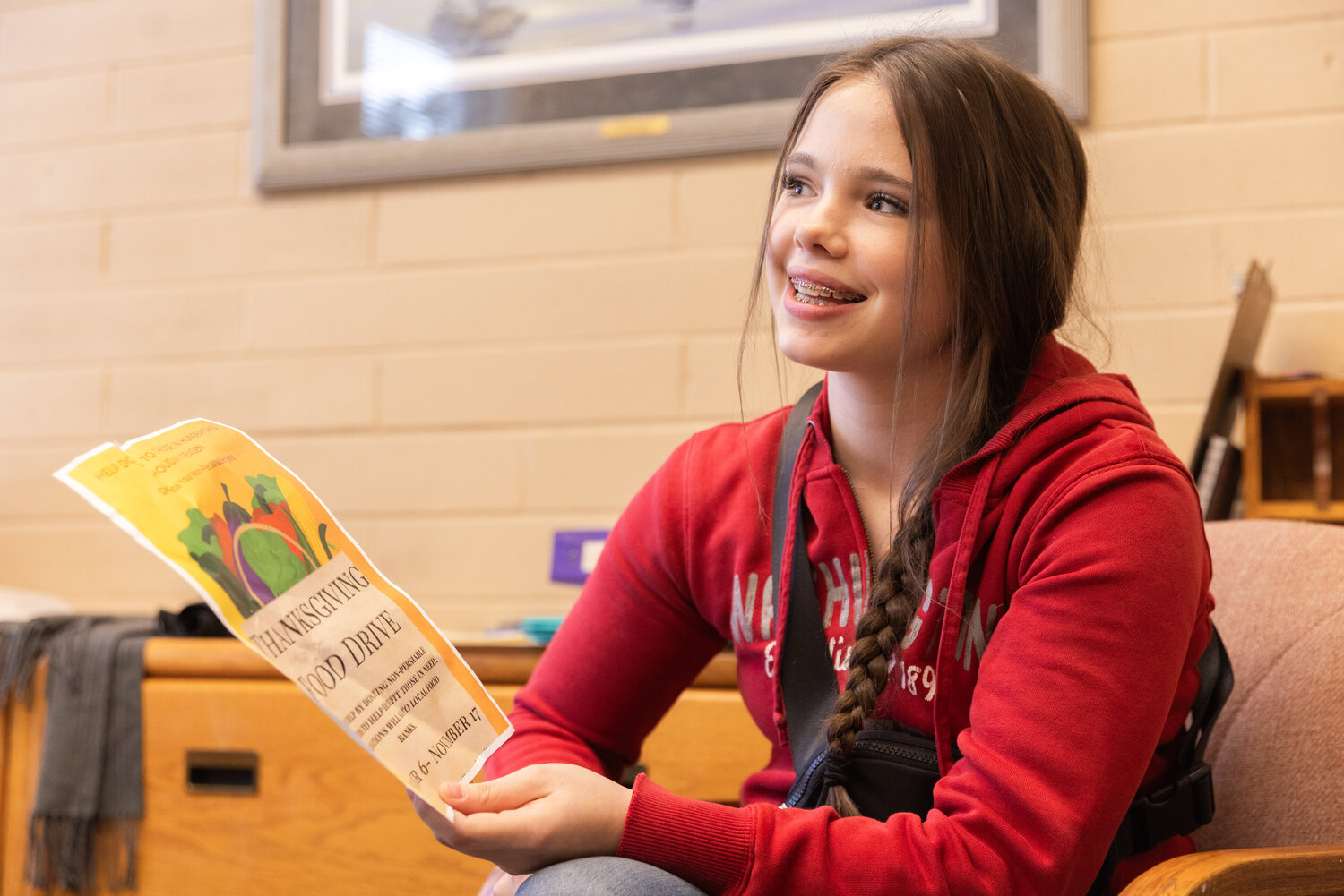 Kate Zandell smiles on Tuesday, Nov. 28, while holding up a Thanksgiving Food Drive flyer she designed at Onalaska High School to help raise awareness around hunger during the holiday season.