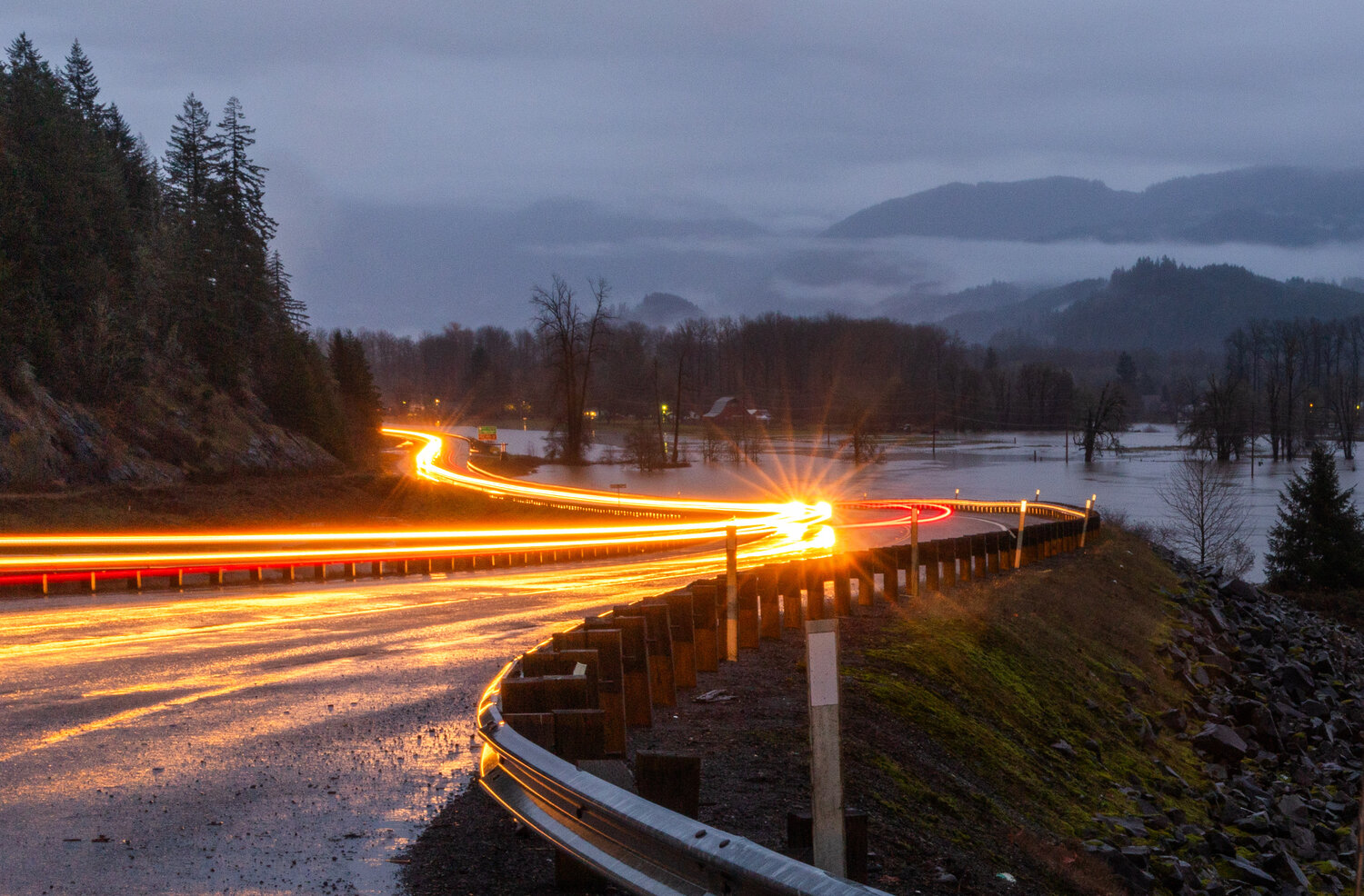 Vehicles drive along U.S. Highway 12 in Randle as water from the Cowlitz River floods portions of the Big Bottom valley on Wednesday, Dec. 6.