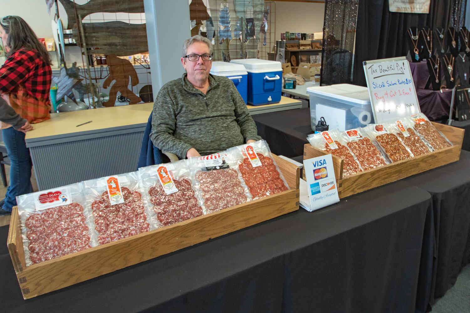 Christopher Leach of The Beautiful Pig sits in front of European-inspired charcuterie meats on Friday, Feb. 2 at the newly opened Northwest Salmon Smokehouse and Artisan Market. Leach smokes and ages the meats himself after he travelled to Europe to gather recipes and has even recieved a Charcuterie Professional Certification from the International Dairy Deli Bakery Association.