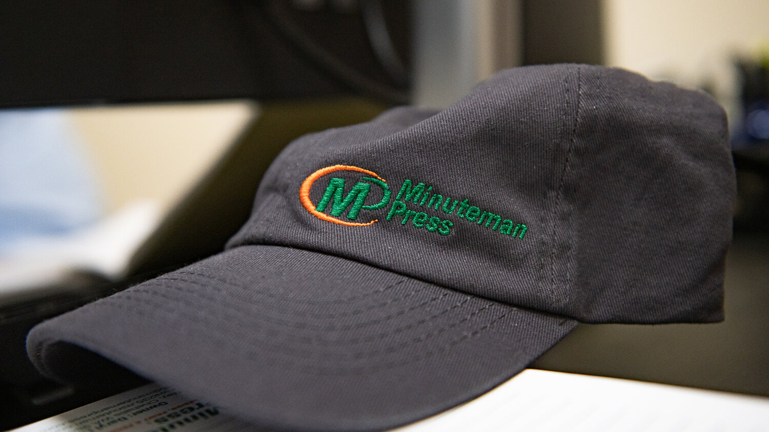 A Minuteman Press custom hat sits atop owner Daryl Lund's desk inside of the Minuteman Press shop in Chehalis on Feb. 8.