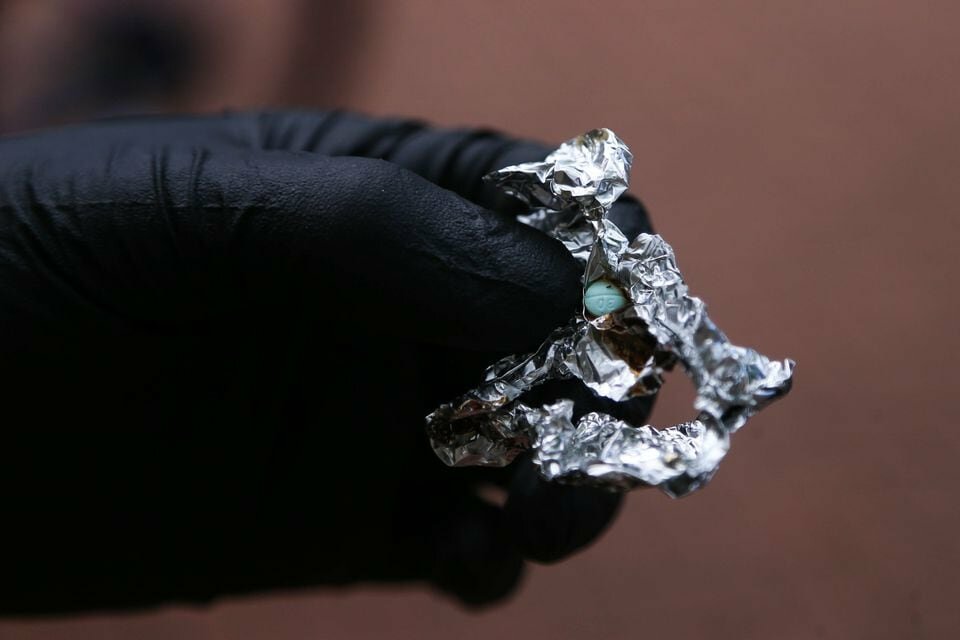 Portland Police Bureau bike patrol holds tin foil containing what is believed to be a fentanyl pill in Old Town on Wednesday, April 27, 2022, after making an arrest.